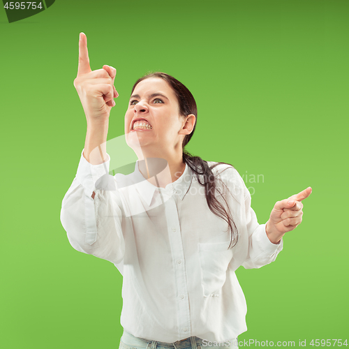 Image of Beautiful female half-length portrait isolated on green studio backgroud. The young emotional surprised woman