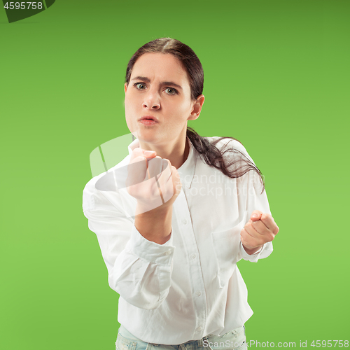 Image of Portrait of an angry woman looking at camera isolated on a green background