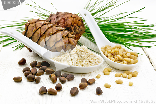 Image of Flour cedar and nuts in two spoons on board