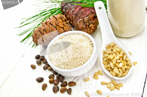 Image of Flour cedar in bowl and nuts in spoon on light board