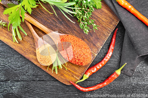 Image of Peppers red and paprika powder in spoon on board top