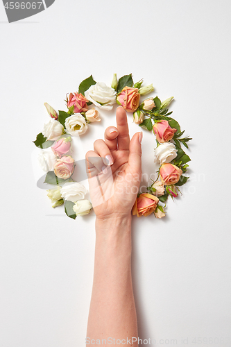 Image of Female\'s hand inside wreath from fresh natural roses flowers.