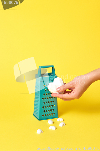 Image of Kitchen grater and plaster heart in a woman\'s hand.