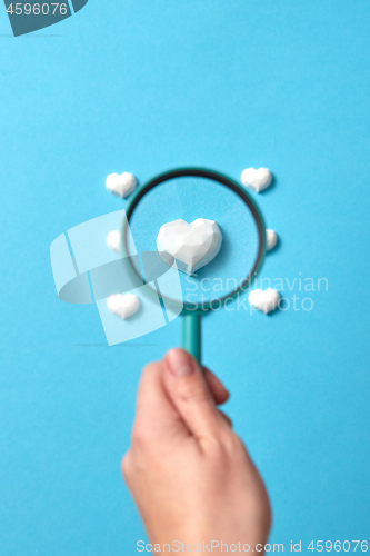 Image of Focused plaster heart in a magnifying glass in the hand.