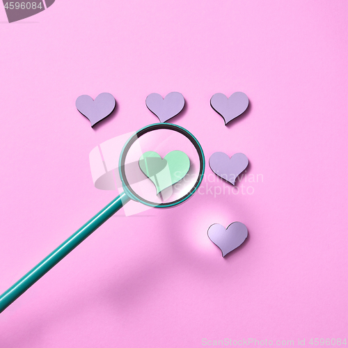 Image of Magnifying glass above hearts pattern.