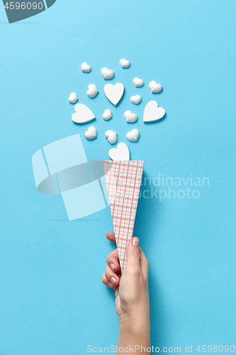 Image of Paper cone with small hearts in woman\'s hand.