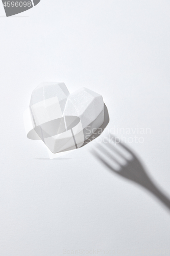 Image of White plaster heart with hard shadow from fork.