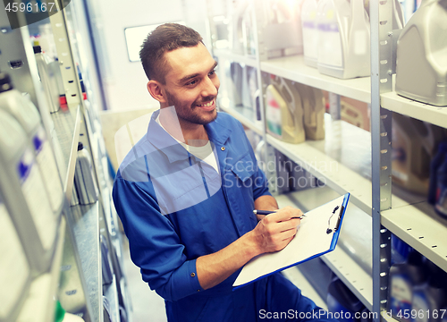 Image of smiling auto mechanic with clipboard at car shop