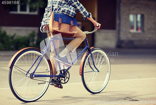 Image of young hipster man with bag riding fixed gear bike