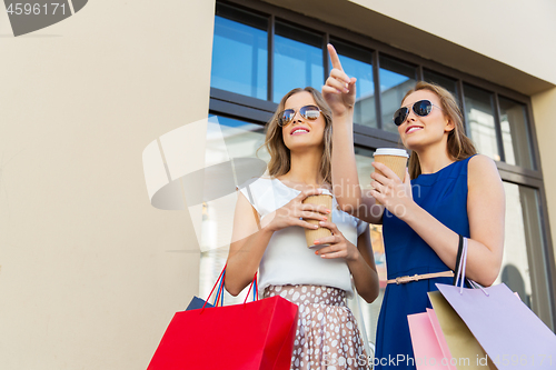 Image of happy women with shopping bags and coffee outdoors