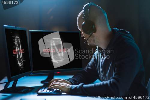 Image of hacker with access denied messages on computers