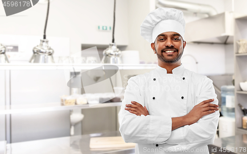 Image of happy indian chef in toque at restaurant kitchen