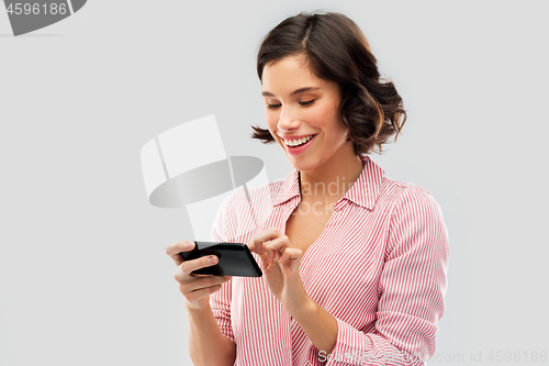 Image of young woman in striped shirt using smartphone