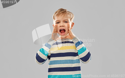 Image of little boy in striped pullover calling someone