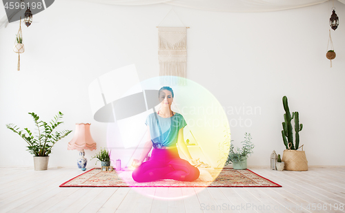 Image of woman meditating in lotus pose at yoga studio