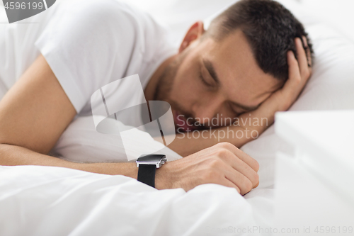 Image of close up of man with smart watch sleeping in bed