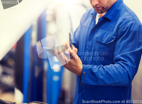 Image of auto mechanic with clipboard at car repair shop