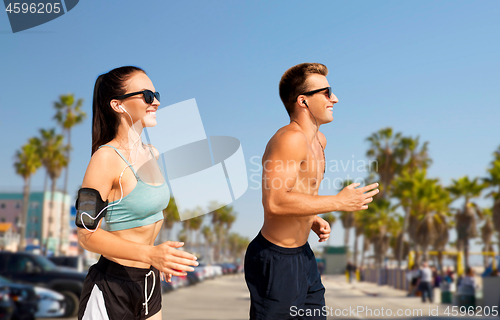 Image of couple with phones and arm bands running on beach