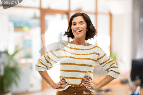 Image of smiling woman in pullover with hands on hips