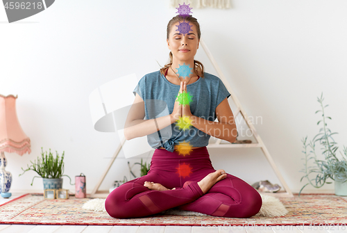 Image of woman meditating in lotus pose at yoga studio