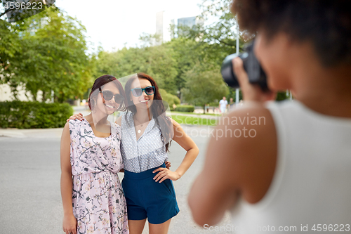 Image of woman photographing her friends in summer park