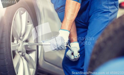 Image of mechanic with screwdriver changing car tire