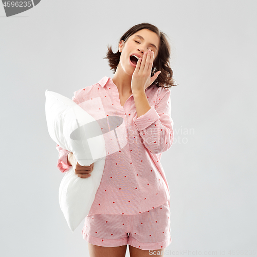 Image of sleepy yawning young woman in pajama with pillow