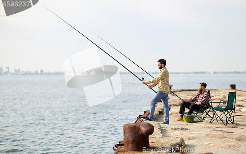 Image of happy friends with fishing rods on pier