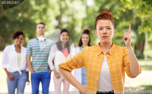 Image of serious red haired teenage girl pointing finger up