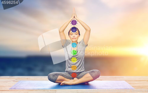 Image of woman doing yoga in lotus pose with seven chakras