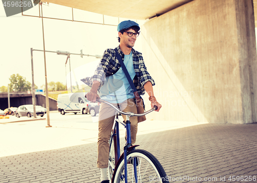 Image of young hipster man with bag riding fixed gear bike