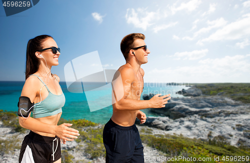 Image of couple with phones and arm bands running on beach