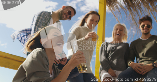 Image of Group of friends having fun on autumn day at beach