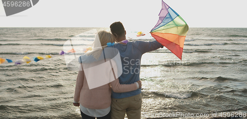 Image of Happy couple having fun with kite on beach