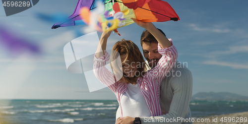 Image of Happy couple having fun with kite on beach