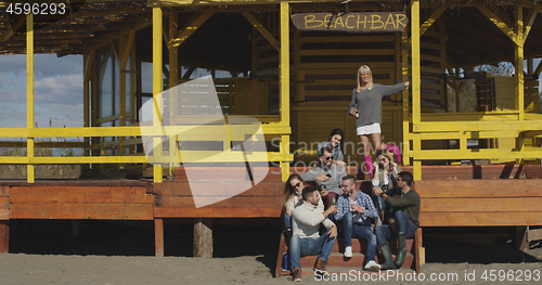 Image of Group of friends having fun on autumn day at beach