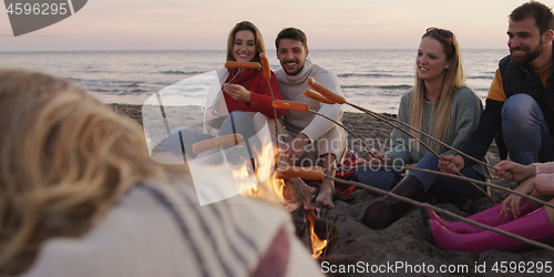 Image of Group Of Young Friends Sitting By The Fire at beach