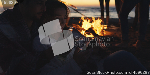 Image of Couple enjoying bonfire with friends on beach