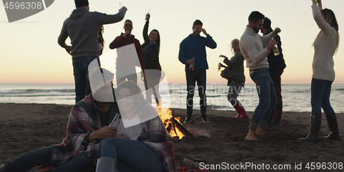 Image of Friends having fun at beach on autumn day