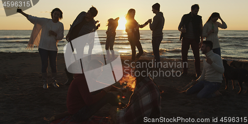 Image of Friends having fun at beach on autumn day