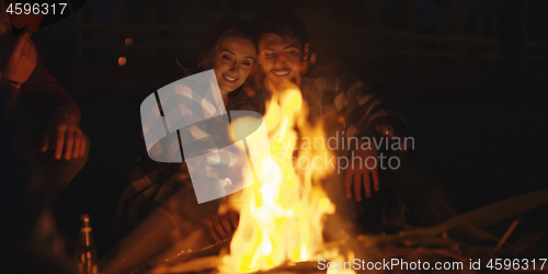 Image of Couple enjoying with friends at night on the beach