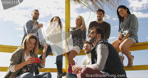 Image of Group of friends having fun on autumn day at beach