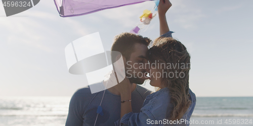 Image of Happy couple having fun with kite on beach