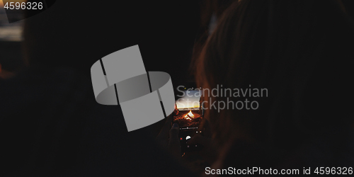 Image of Couple taking photos beside campfire on beach