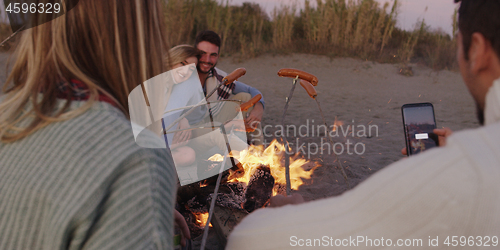 Image of Group Of Young Friends Sitting By The Fire at beach