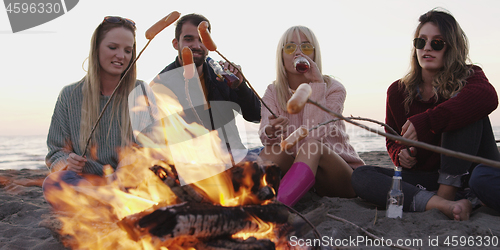 Image of Group Of Young Friends Sitting By The Fire at beach