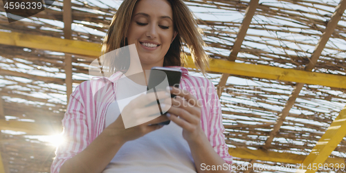 Image of Smartphone Woman Texting On Cell Phone At Beach