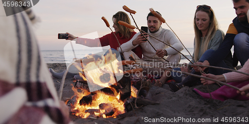 Image of Group Of Young Friends Sitting By The Fire at beach