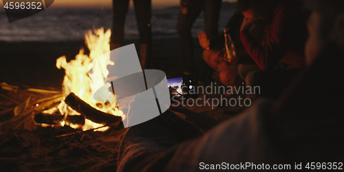 Image of Couple taking photos beside campfire on beach