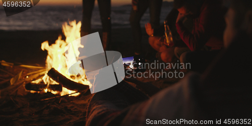 Image of Couple taking photos beside campfire on beach